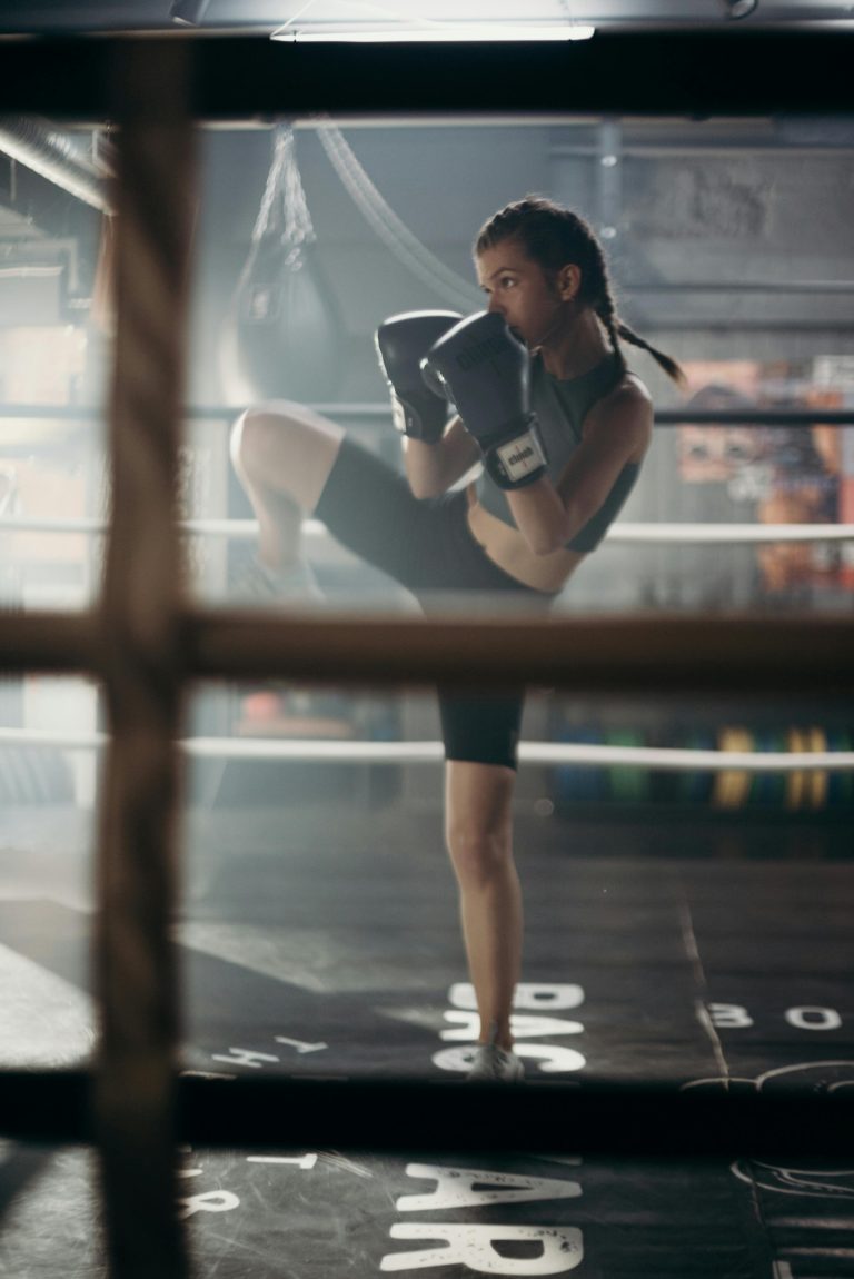Determined young woman practicing kickboxing in a gym with focused stance.